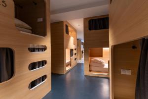 CALM Appart' & Hostel في ليل: غرفة بجدران خشبية وممر مع أسرة