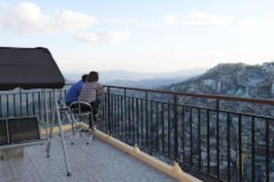 two people sitting on a balcony looking at the city at The Lushai Inn, Aizwal in Āīzawl