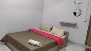 un piccolo letto in una camera bianca con una coperta rossa di The Lushai Inn, Aizwal ad Āīzawl