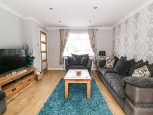 uma sala de estar com um sofá e uma televisão em The Whyte Retreat em Hornsea
