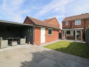 a brick house with a patio and a yard at The Whyte Retreat in Hornsea