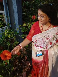 een vrouw in een jurk die naast een bloem staat bij Jheelam Homestay in Bhopal