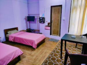 um quarto com 2 camas, uma secretária e uma mesa em Chawngthu Lodge,Aizawl em Āīzawl