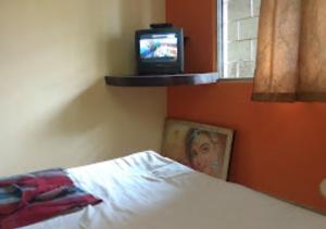 1 dormitorio con 1 cama y TV en la ventana en Hotel Basera Odisha, en Rourkela