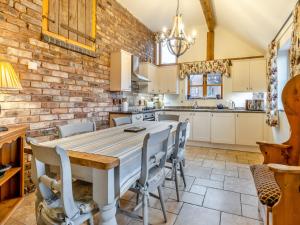 a kitchen with a table and chairs and a brick wall at The Barn- Uk45536 in Buildwas