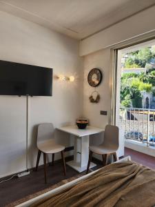 Habitación con mesa, 2 sillas y ventana en Your favorite apartments, en Menton