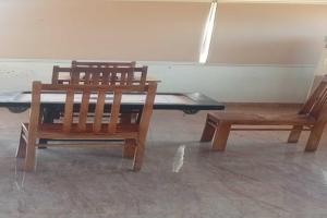 twee houten stoelen en een tafel en een bank bij Nikhara Fort Resorts in Penukonda