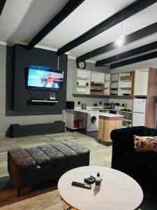 uma sala de estar com um sofá e uma televisão na parede em Maison De luxe em Thohoyandou