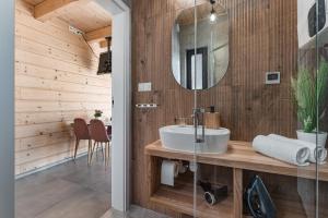 ein Bad mit einem Waschbecken und einem Spiegel in der Unterkunft Górski Horyzont - domki nad jeziorem z widokiem na Tatry in Kluszkowce
