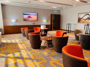 a hotel lobby with orange chairs and a flat screen tv at Lavender Hotel Al Nahda Dubai in Dubai