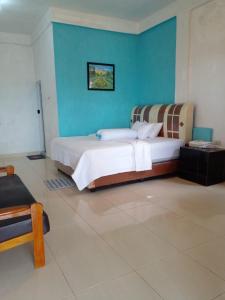 a bedroom with a large bed with a blue wall at TOHO NIAS in Telukdalam