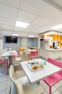 a cafeteria with tables and chairs with a plate of food at Premiere Classe Deauville Touques in Deauville
