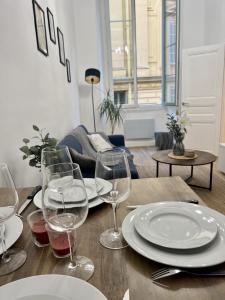a wooden table with plates and wine glasses on it at Sublime Appartement 2 pièces au cœur de la Vieille Ville in Nice