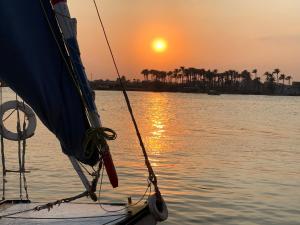 un barco en el agua con la puesta de sol en el fondo en Zoser Pyramids View- Foreiigners only en El Cairo