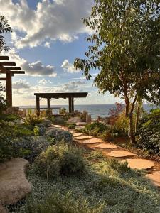 un jardín con un banco y el océano en el fondo en Al Hatzuk Israel, en Bet Yannay