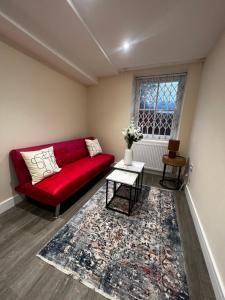 um sofá vermelho numa sala de estar com uma janela em Flat in London em Londres