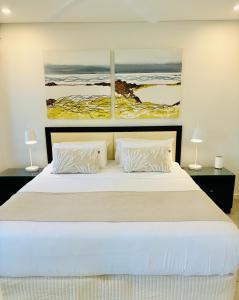 a bedroom with a large bed with two paintings on the wall at Lagoon Swimout Absolute Pool Front - Slice of Paradise - Sea Temple Pt Douglas in Port Douglas