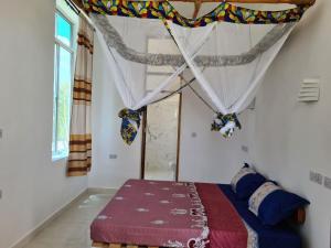 1 dormitorio con cama con dosel y ventana en Five Seasons Zanzibar opposite Mnemba island Hotel, en Makunge