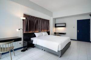 a bedroom with a white bed and a desk and a bed sidx sidx at Capitel Rama 4 in Bangkok