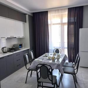 a kitchen with a table and chairs and a kitchen with a table and a table at Karavan Saray house in Türkistan