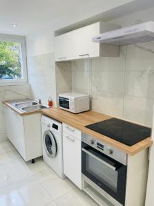 a white kitchen with a microwave and a sink at Jolie T3 à Colomiers in Colomiers