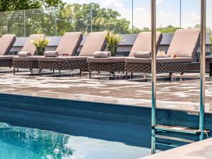 a row of lounge chairs sitting next to a swimming pool at Mercure Orléans Centre Bords de Loire in Orléans