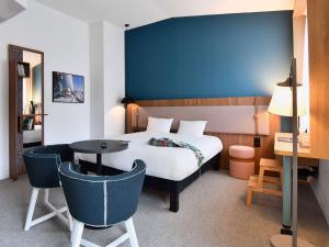 - une chambre avec un lit, une table et des chaises dans l'établissement ibis Styles Brest Centre Port, à Brest