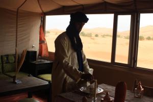 a man standing in a room with a table in a tent at Shooting Stars Camp in Merzouga