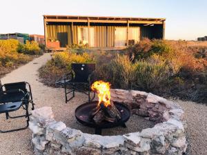 a fire pit with two chairs and a building at Trekosglamping #2 in Vredenburg