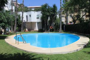 a swimming pool in a yard with trees and a house at Marbella Apartment in Marbella