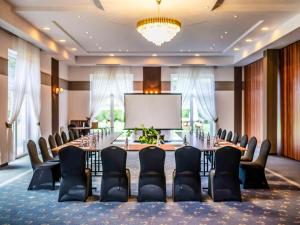 a conference room with a table and chairs and a screen at Mercure Racławice Dosłońce Conference&SPA in Racławice