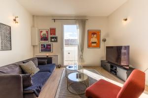 ein Wohnzimmer mit einem Sofa und einem TV in der Unterkunft Galerie Mediterranee - Premiere conciergerie in Montpellier