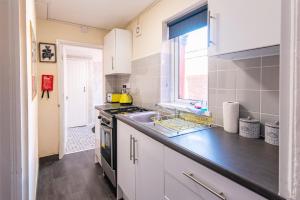 uma cozinha com armários brancos e uma bancada em Imeary - 3BR Terraced Near S. Shields em South Shields
