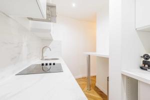 una cocina blanca con fregadero y encimeras blancas en Chic Parisian Retreat - Porte de Montreuil - 2, en París