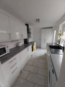 a kitchen with white cabinets and a tile floor at Finsbury Workstays UK in Middlesbrough