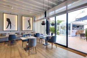 uma sala de jantar com mesas e cadeiras e janelas grandes em Barceló Costa Ballena Golf & Spa em Costa Ballena