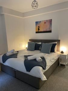 a bedroom with a large bed with blue pillows at The Sand Bank - Flat 1 Abchurch Chambers BH1 in Bournemouth