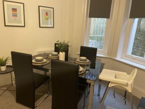 a dining room with a black table and chairs at The Sand Bank - Flat 1 Abchurch Chambers BH1 in Bournemouth