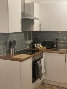 een keuken met witte kasten en een fornuis met oven bij The Sand Bank - Flat 1 Abchurch Chambers BH1 in Bournemouth