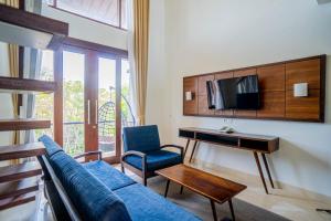 een woonkamer met een bank, een tafel en een tv bij djabu Echo Beach Hotel in Canggu