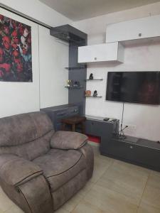 uma sala de estar com um sofá e uma televisão de ecrã plano em Tiger Den stylish studio Apartment em Chengalpattu