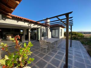 un patio avec une table et des chaises sous une pergola dans l'établissement Coastal & Country Living in Langebaan, à Langebaan