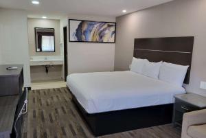 a bedroom with a large bed and a desk at Travelodge by Wyndham Buena Park in Buena Park