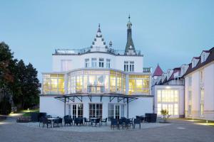 ein großes weißes Gebäude mit Stühlen davor in der Unterkunft Dorint Parkhotel Meißen in Meißen