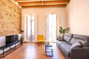 uma sala de estar com um sofá e uma parede de tijolos em Apartamentos turísticos Decumano Romano em Cartagena