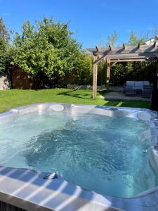 una bañera de hidromasaje en un patio trasero con pérgola en Modern, central bungalow with Luxury Hot tub en Bournemouth