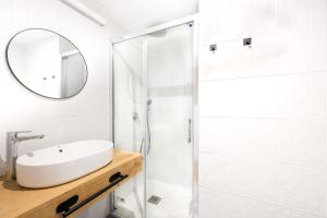 y baño blanco con lavabo y ducha. en Apartamentos turísticos Decumano Romano, en Cartagena