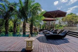 een patio met een zwarte bank en een parasol bij djabu Echo Beach Hotel in Canggu