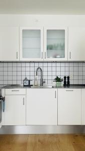 kuchnia z białymi szafkami i zlewem w obiekcie ApartmentInCopenhagen Apartment 1574 w Kopenhadze