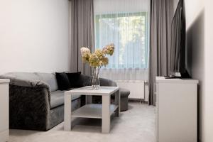 a living room with a couch and a table with flowers at Hotel Promenada Biznes & Wypoczynek in Radom